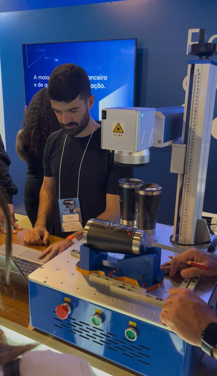 Operador personalizando copos em uma máquina de gravação a laser durante um evento